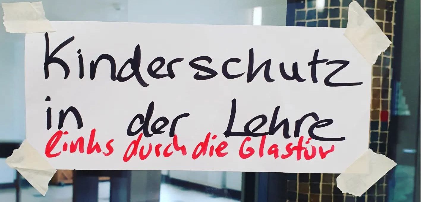 Headerbild Einblicke und Referenzen - Hinweis zu Kinderschutz in der Lehre, auf Papier geschrieben und an eine Glastür geklebt.